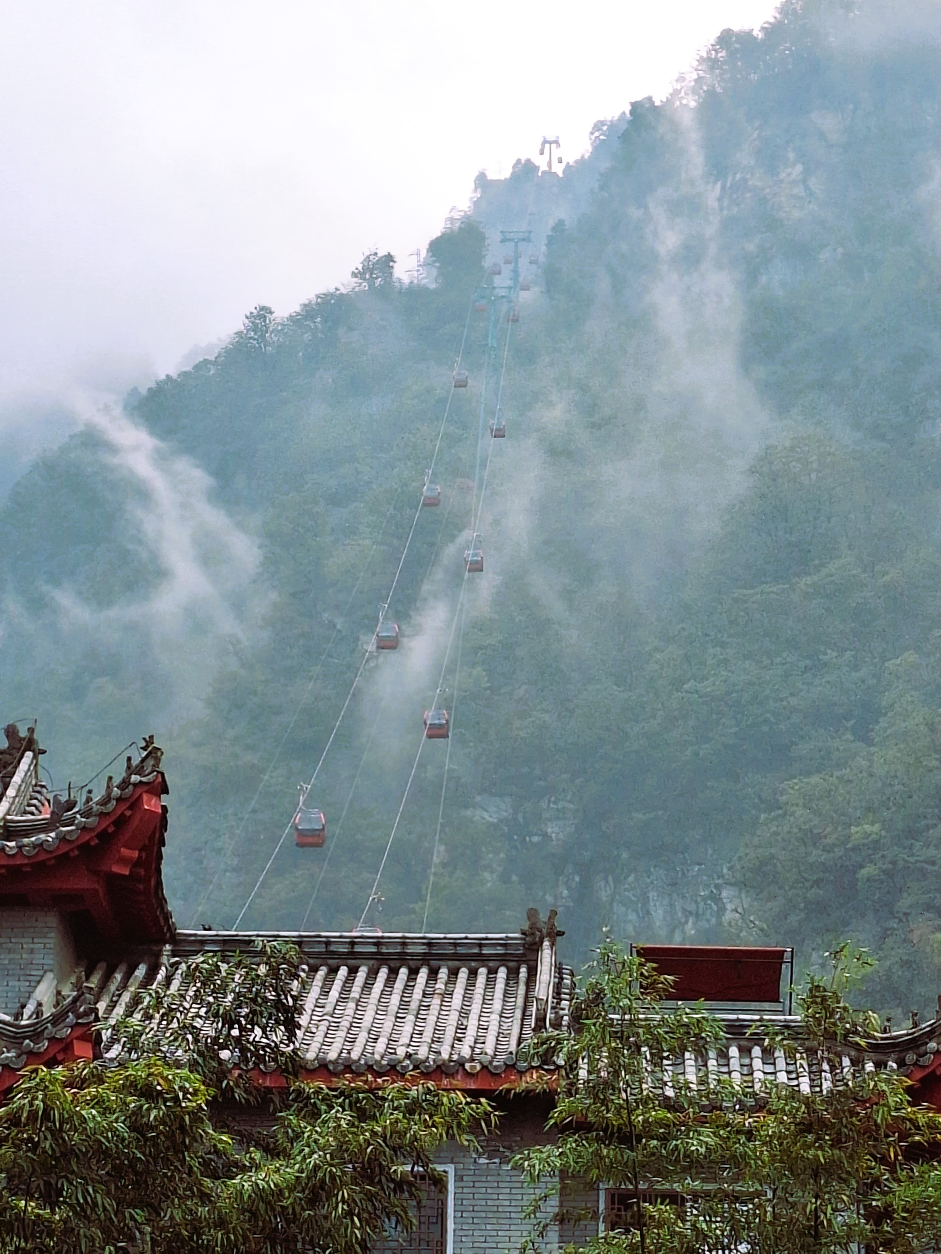 Cable cars rising through misty mountain scenery at Wudang Mountain in Shiyan.