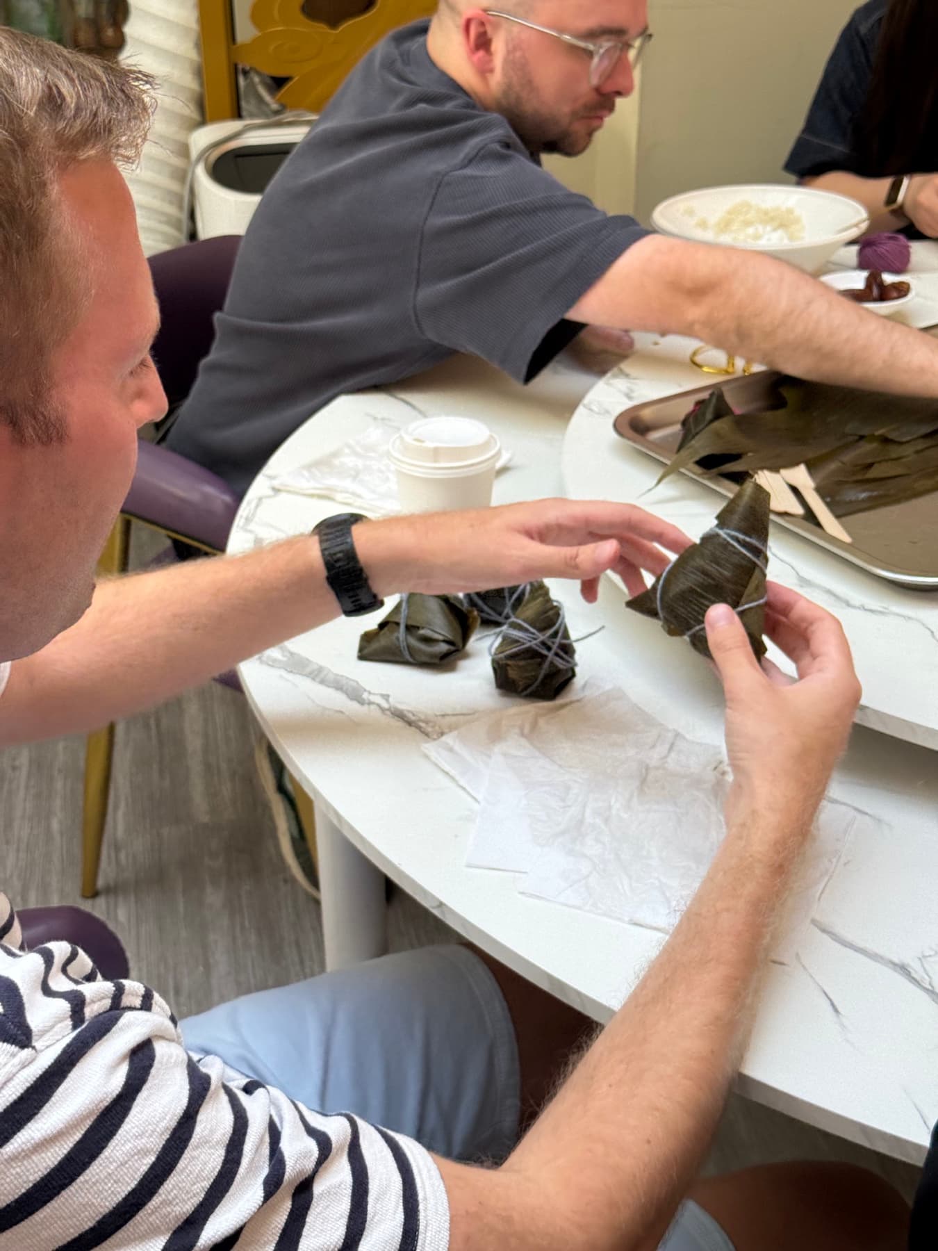 Hands tying wrapped zongzi with string at a London Chinese culture event