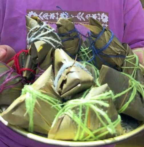 Cropped view of finished handmade zongzi tied with colourful string at a London Dragon Boat Festival workshop