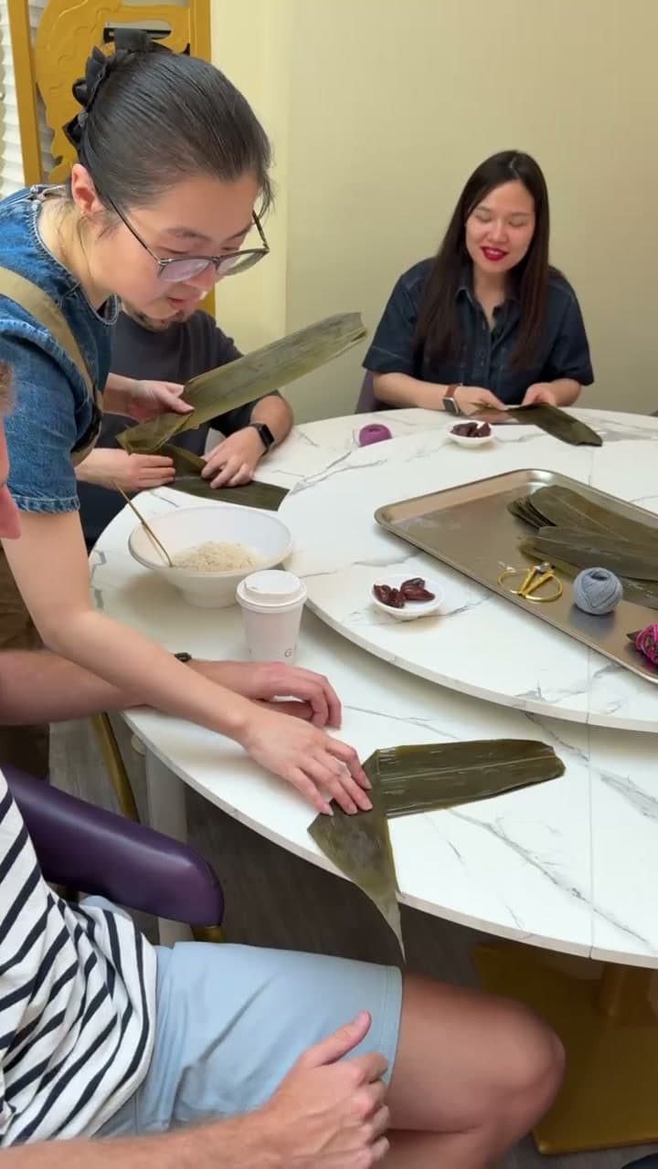 Participants learning to fold lotus leaves during a hands-on zongzi workshop in London